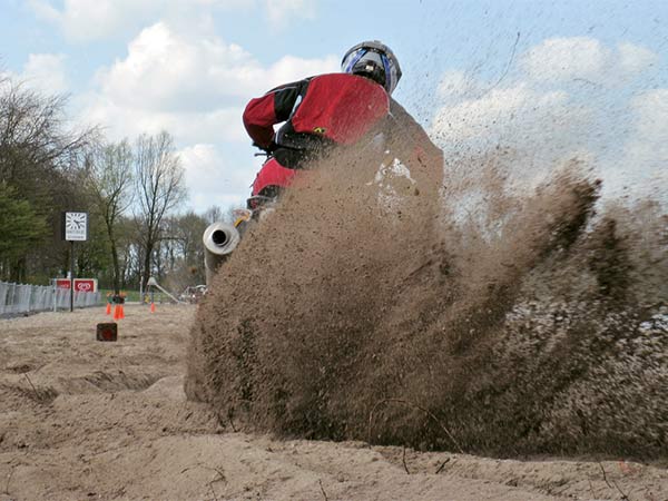 Een crosser gooit zand op