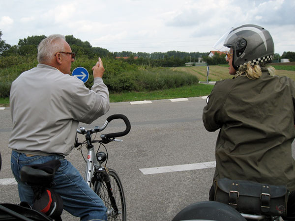 Meneer op fiets wijst de weg aan Sylvia op motor