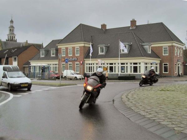 Twee motorrijders op een natte rotonde