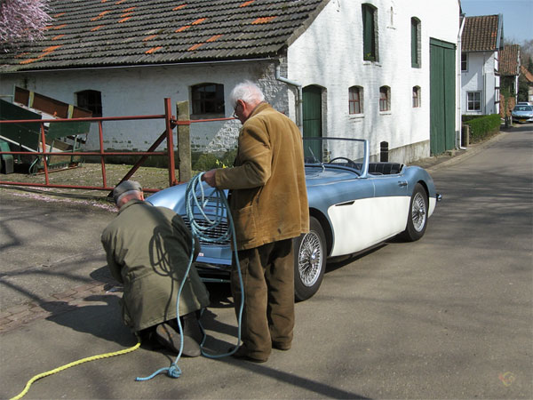 Twee mannen met een stuk touw en een klassieke auto