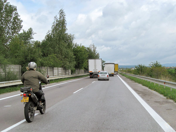 Motorrijder achter vrachtwagen die vrachtwagen inhaalt