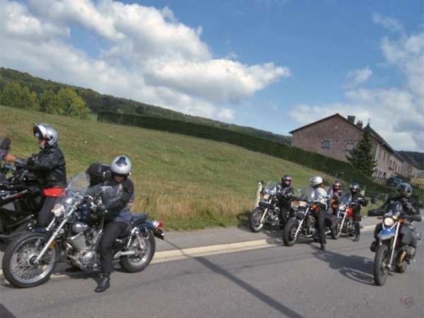 Stilstaande motorrijders, eentje kijkt in de spiegel, een ander staat te kletsen